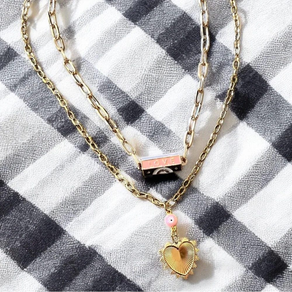 Gold toned chains with black, white, gold, and pastel pink enamel charms.